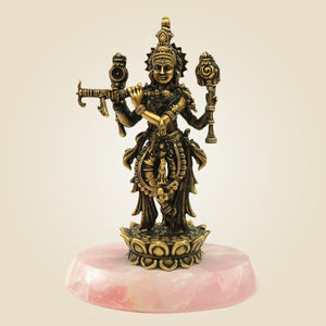 Bronze statue of a deity on a pink stone base against a beige background