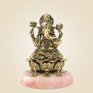Bronze statue of a deity on a pink stone base against a beige background