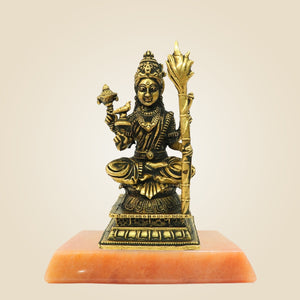 Bronze statue of a deity on an orange pedestal against a beige background