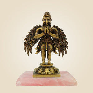Bronze statue of a deity on a pink base against a beige background