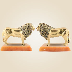 Two gold lion figurines facing each other on a beige background