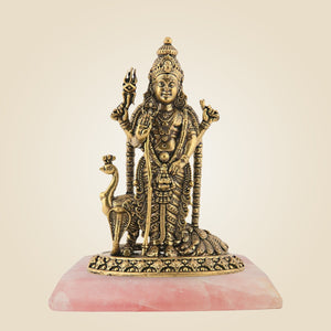Bronze statue of a deity on a pink stone base against a beige background