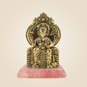 Gold-colored deity statue on a pink base against a beige background