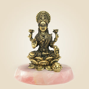 Bronze statue of a seated figure on a pink marble base against a beige background