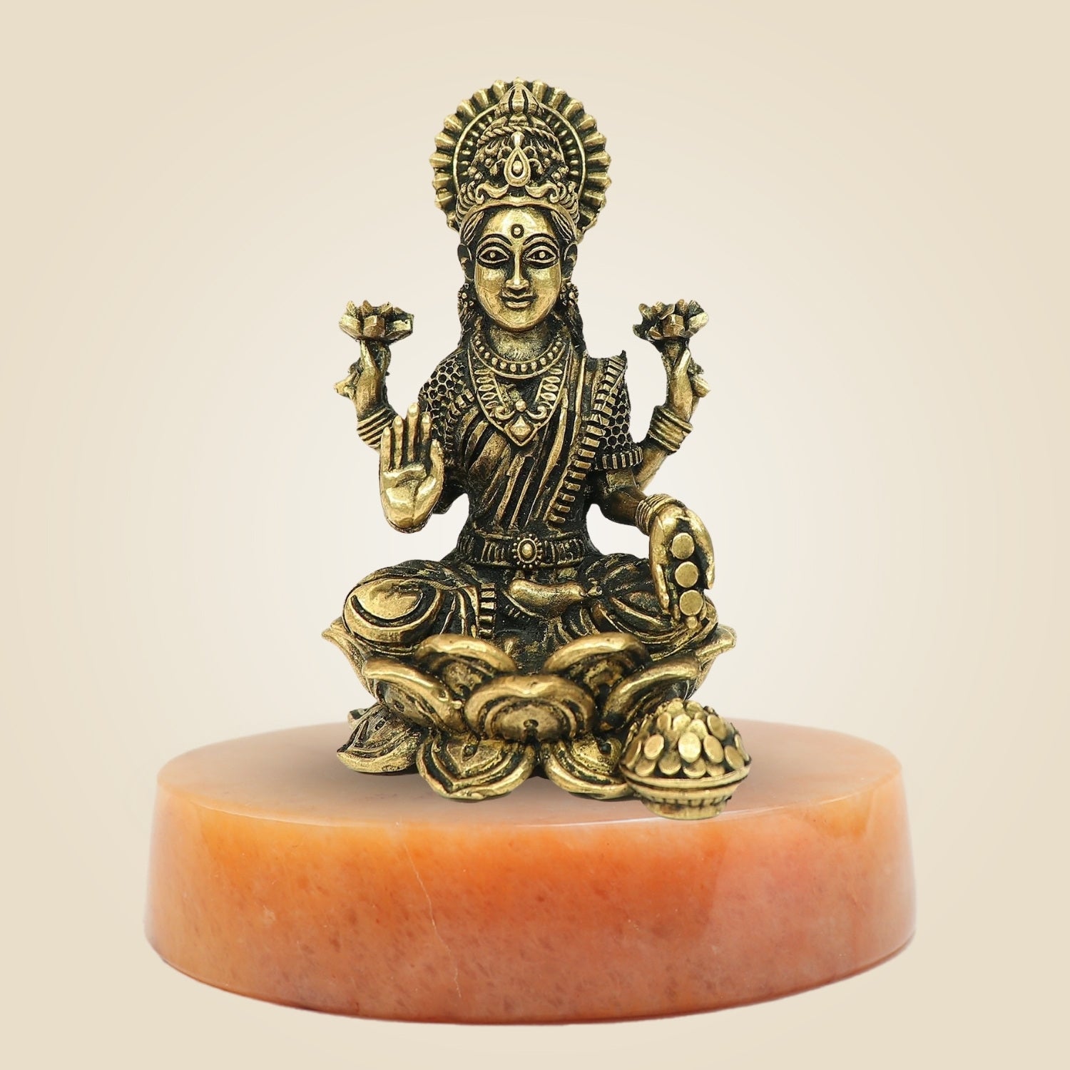 Bronze statue of a seated figure on a beige background