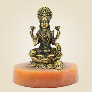 Bronze statue of a seated figure on a beige background