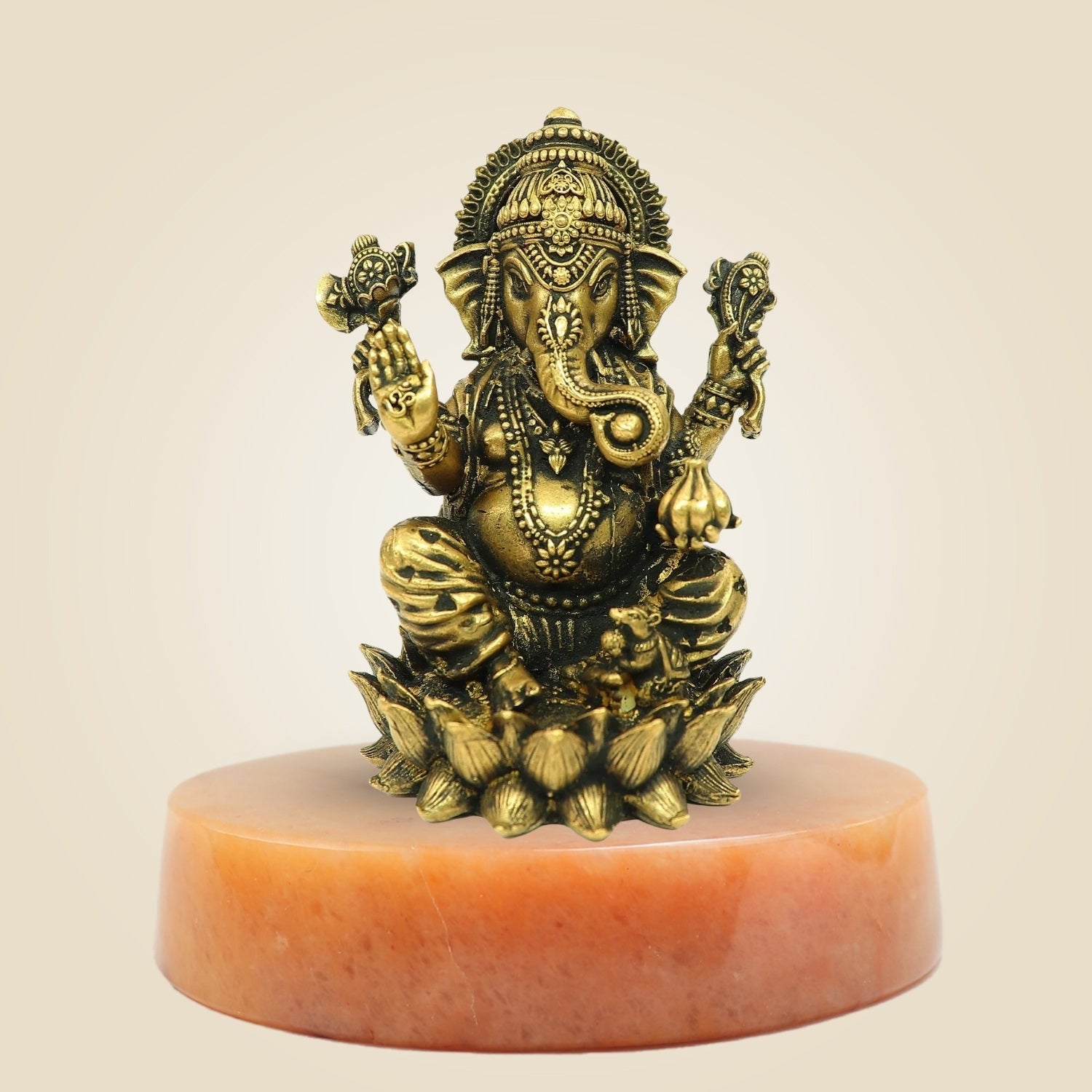 Bronze statue of a deity on a pink pedestal against a beige background