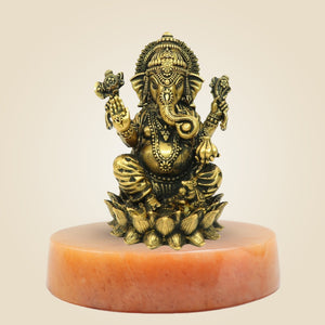 Bronze statue of a deity on a pink pedestal against a beige background