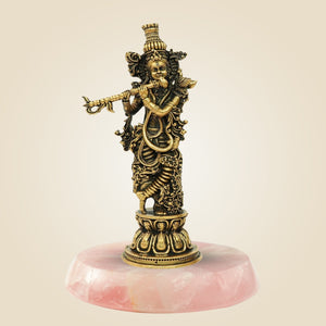 Bronze statue of a deity on a pink marble base against a beige background