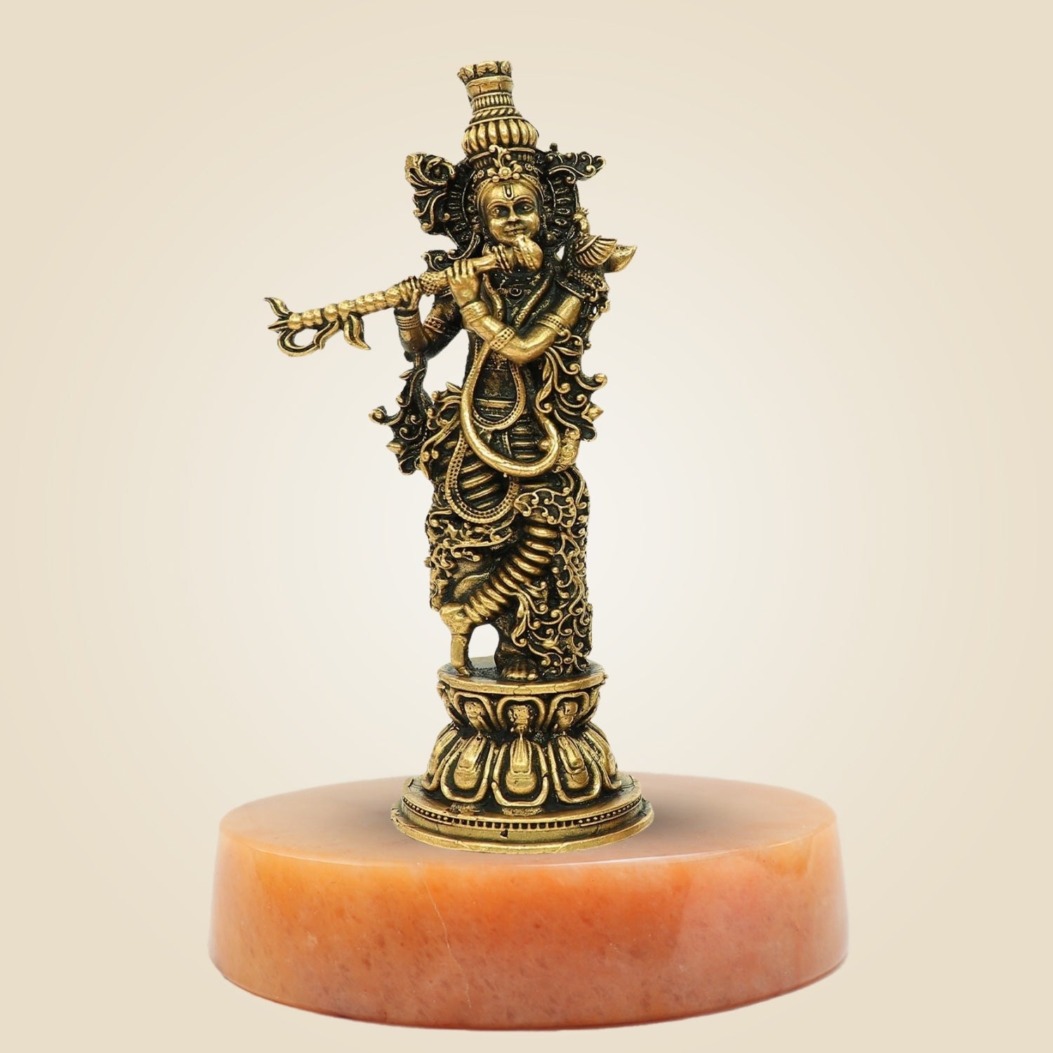 Bronze statue of a deity on a pink marble base against a beige background