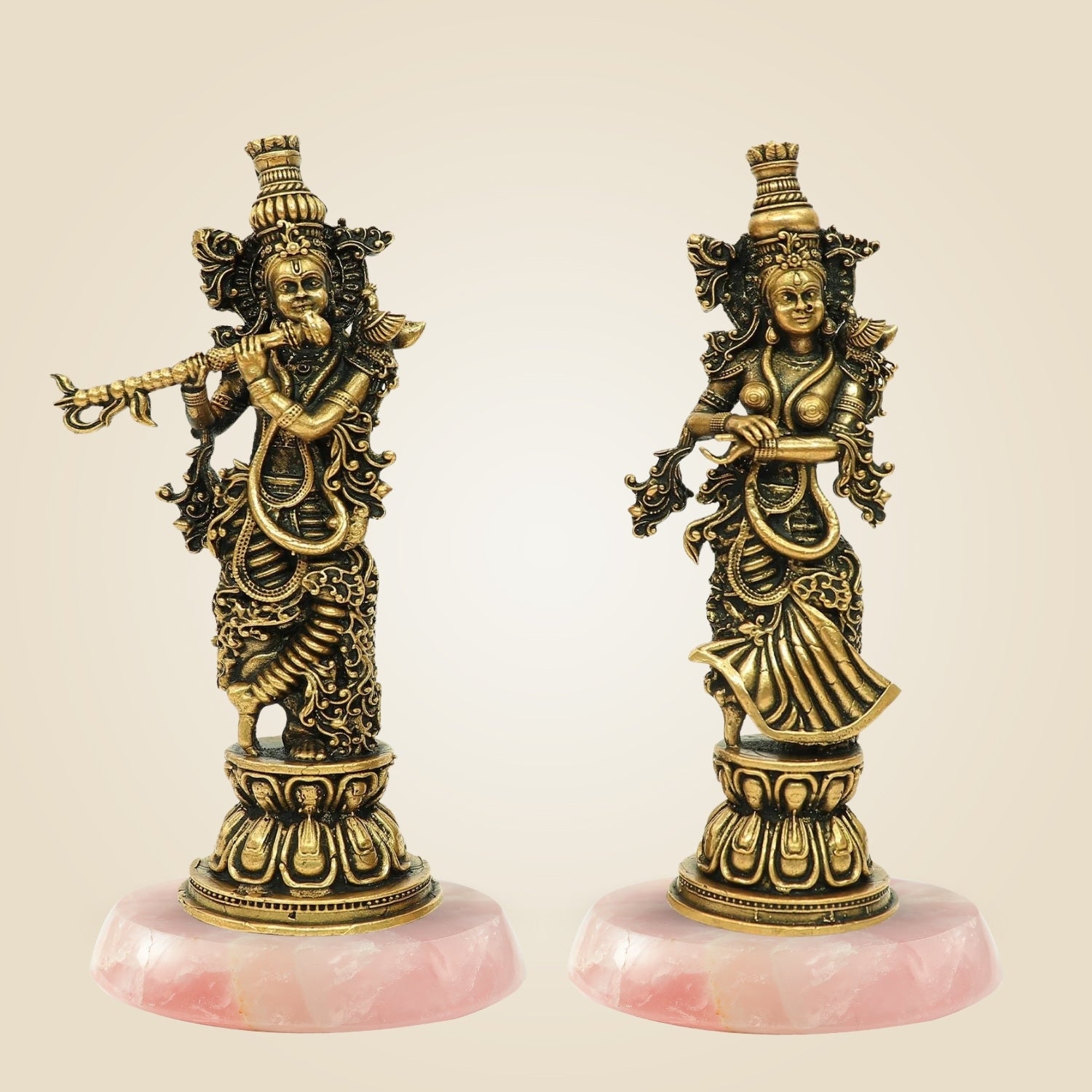 Two ornate statues on pink bases against a beige background