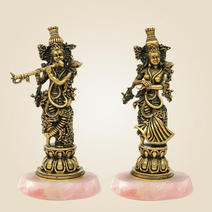 Two ornate statues on pink bases against a beige background