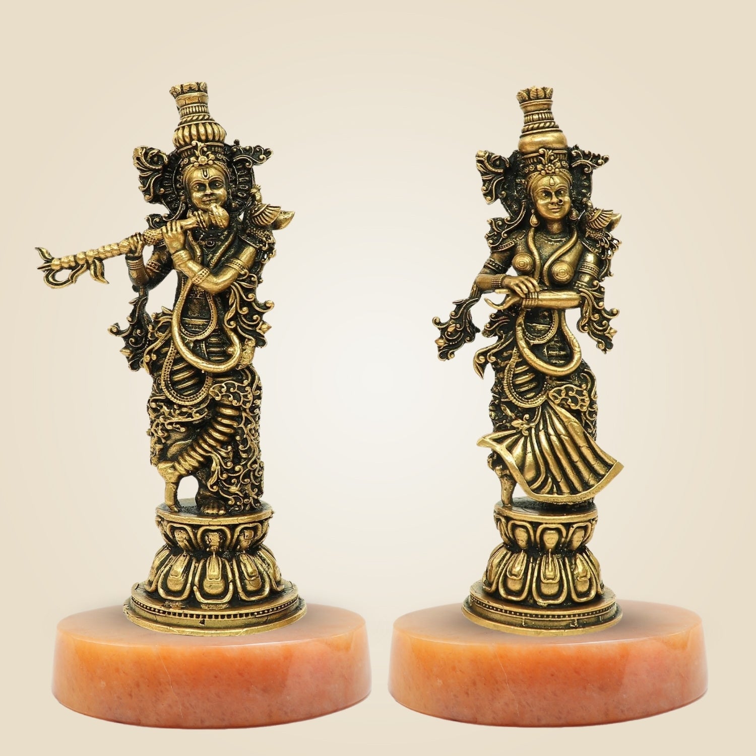 Two ornate statues on red bases against a beige background