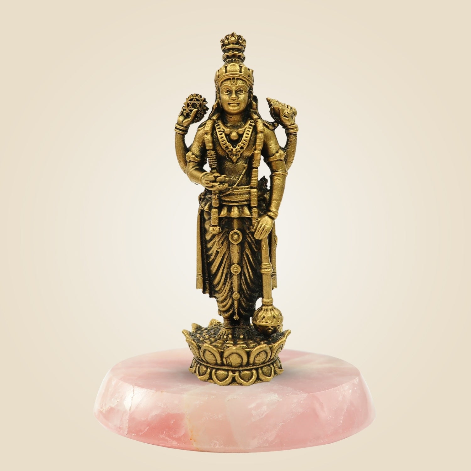 Bronze statue of a deity on a pink stone base against a beige background