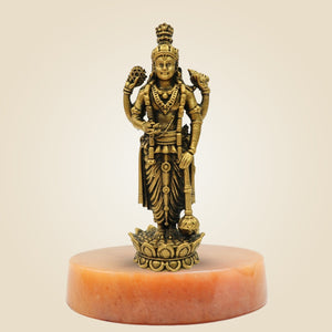 Bronze statue of a deity on a pink pedestal against a beige background