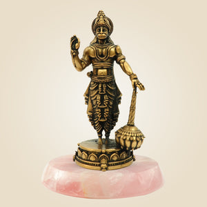 Bronze statue on a pink stone base against a beige background