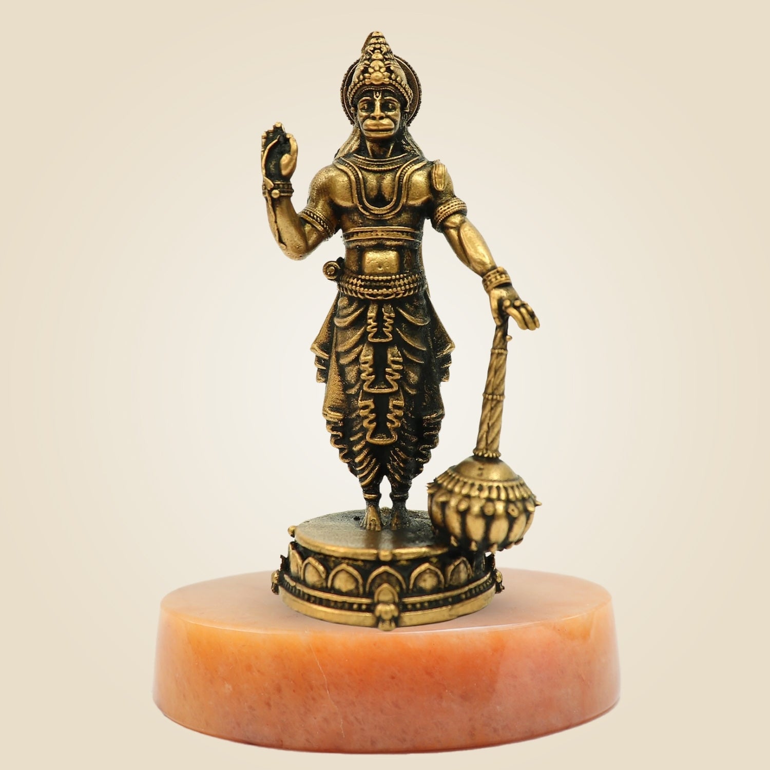 Bronze statue of a deity on a pink pedestal against a beige background