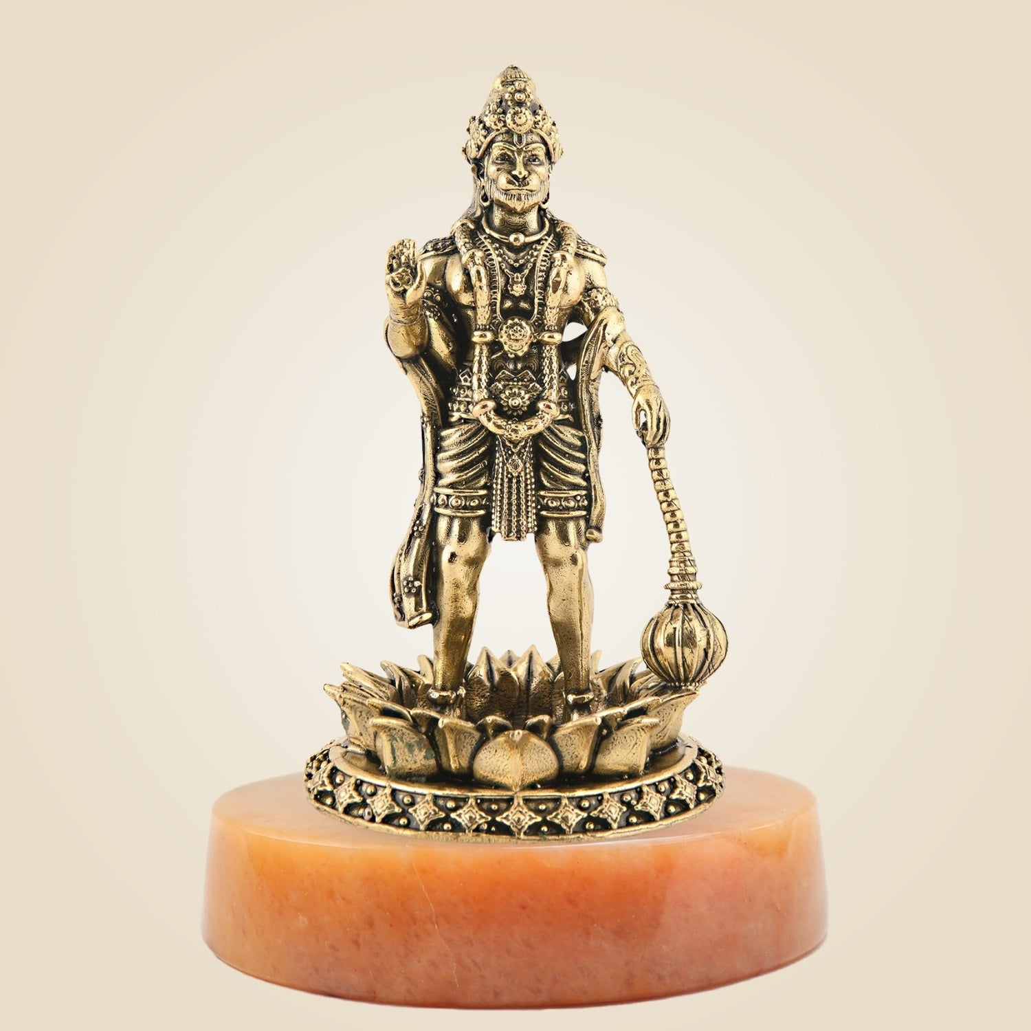 Bronze statue of a deity on a pink stone base against a beige background