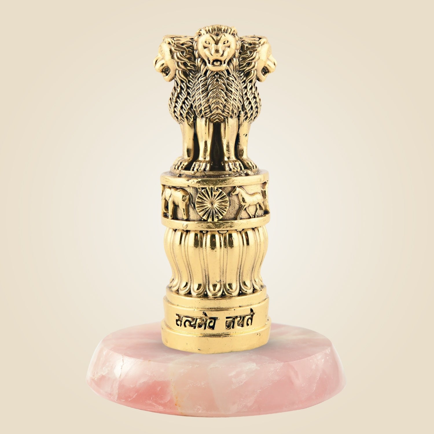 Decorative gold emblem with lion heads on a pink stone base against a beige background