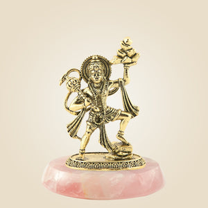 Gold-colored statue on a pink stone base against a beige background