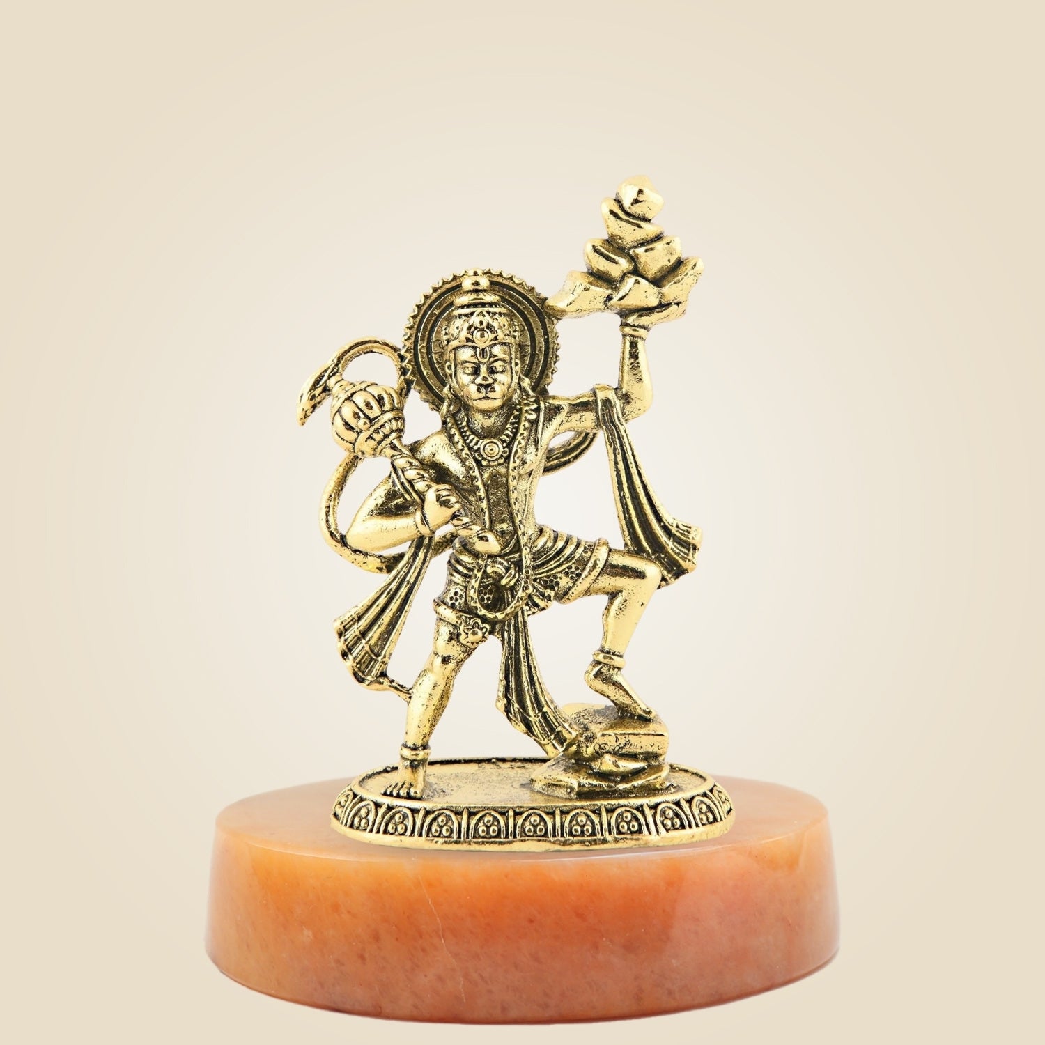 Gold-colored statue on a red base against a beige background