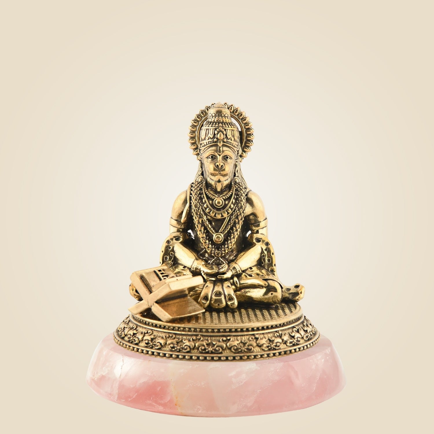 Decorative statue of a seated figure on a pink stone base against a beige background