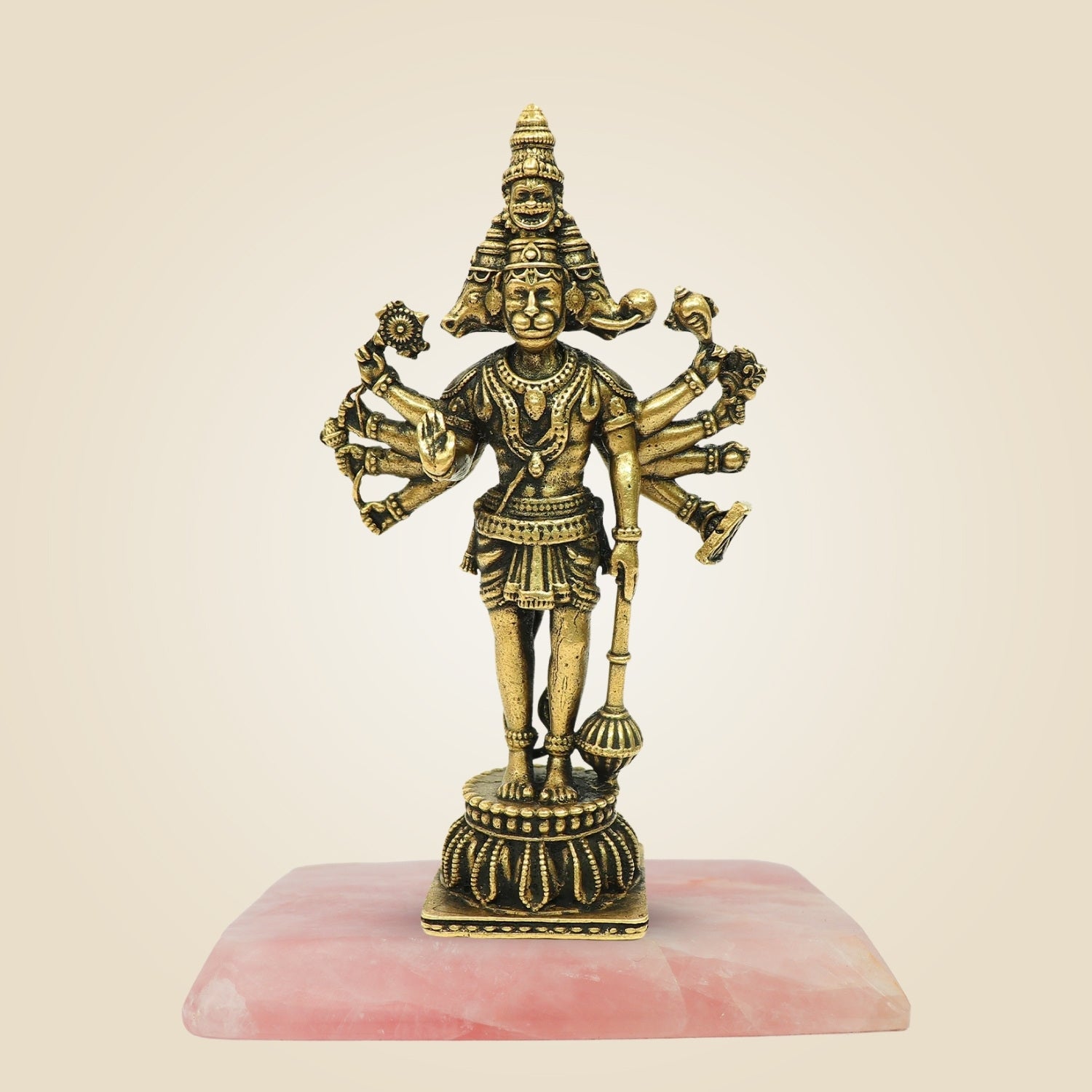 Bronze statue of a deity with multiple arms on a pink stone base against a beige background