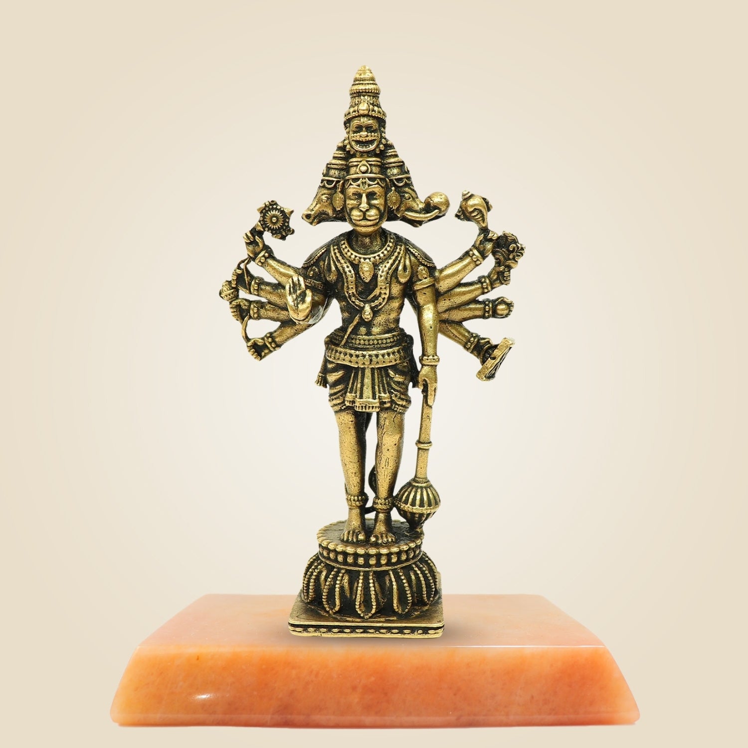 Bronze statue of a deity on an orange pedestal against a beige background