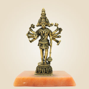 Bronze statue of a deity on an orange pedestal against a beige background