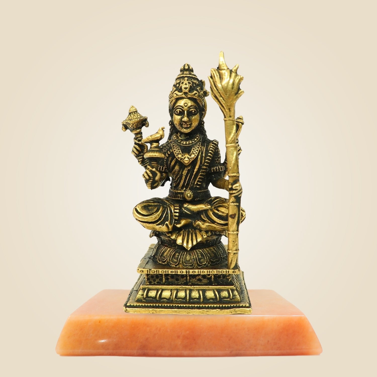 Bronze statue of a deity on an orange pedestal against a beige background