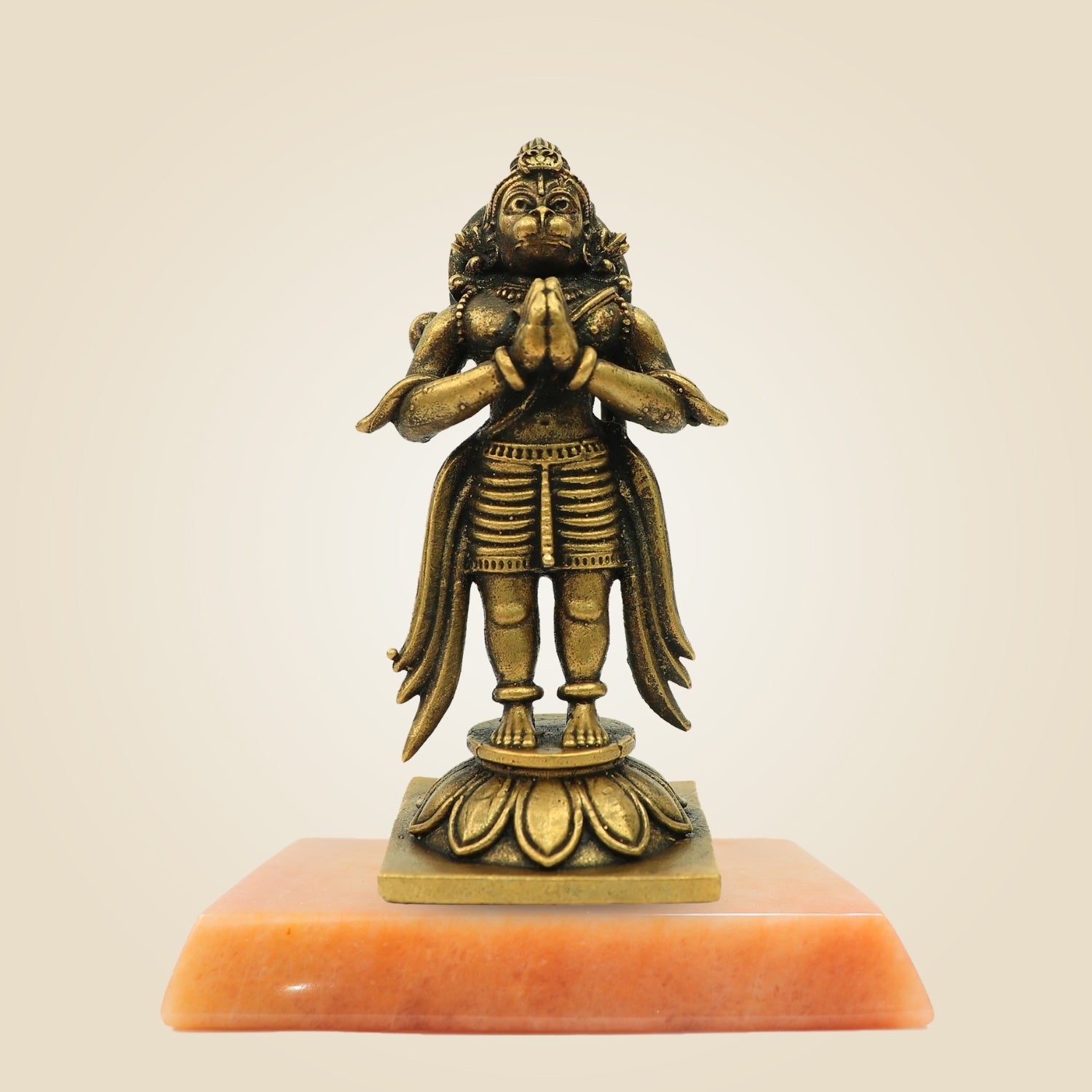 Bronze statue on a pink pedestal against a beige background