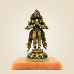 Bronze statue on a pink pedestal against a beige background