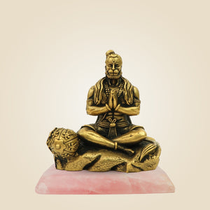 Bronze statue of a seated figure on a pink base with a beige background
