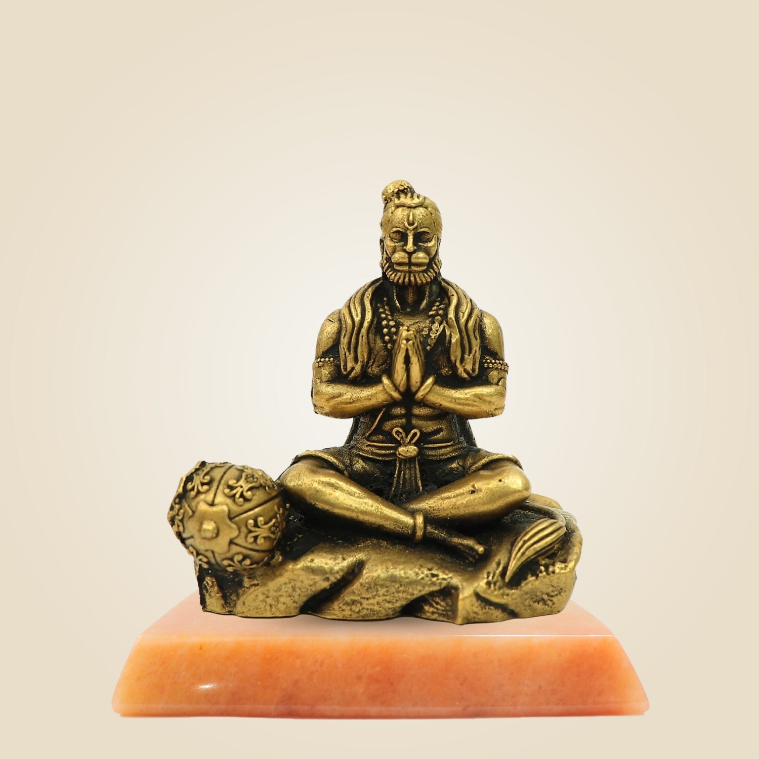 Bronze statue of a seated figure on a beige background