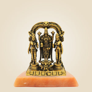 Bronze statue of three figures on a pink stone base against a beige background