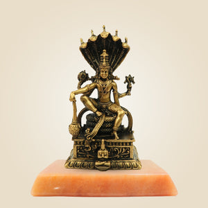 Bronze statue of a deity on an orange pedestal against a beige background