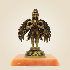 Bronze statue of a deity on an orange pedestal against a beige background