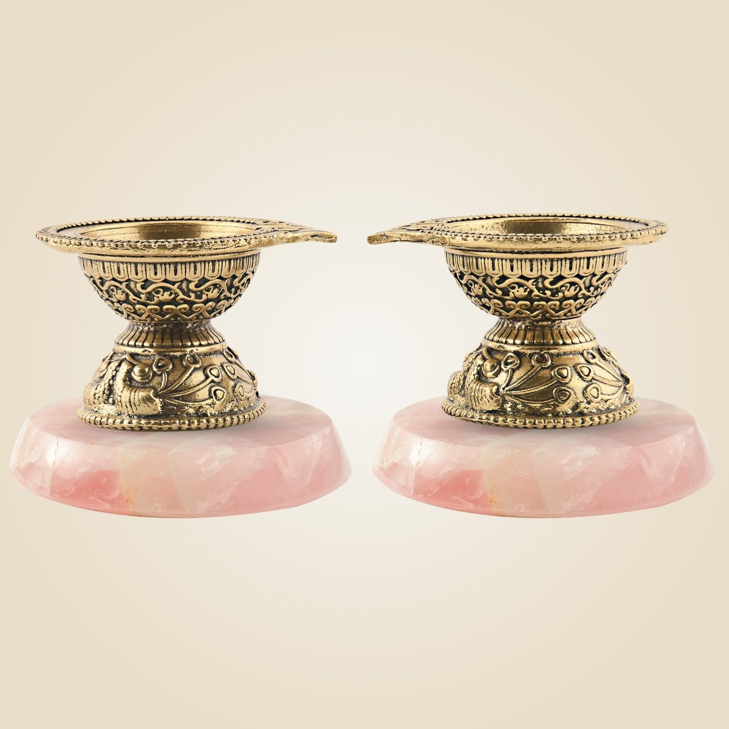 Two ornate candle holders with pink bases on a beige background