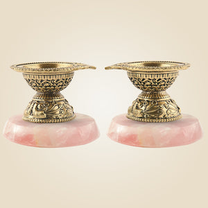 Two ornate candle holders with pink bases on a beige background