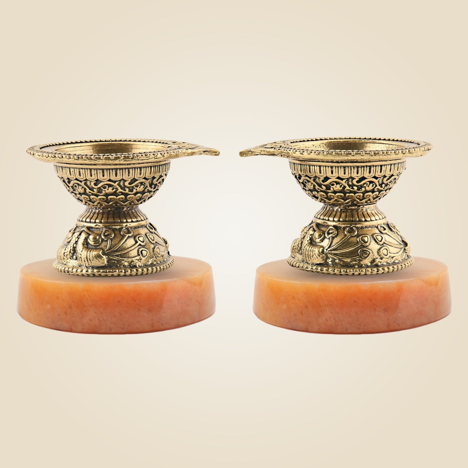 Two ornate brass candle holders on a beige background