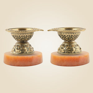 Two ornate brass candle holders on a beige background