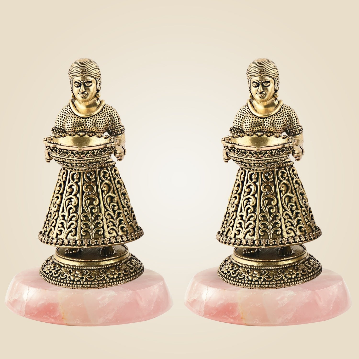 Two ornate bronze figures on pink stone bases against a beige background