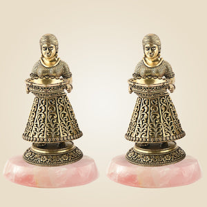 Two ornate bronze figures on pink stone bases against a beige background