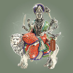 Decorative figurine of a deity on a lion with colorful embellishments